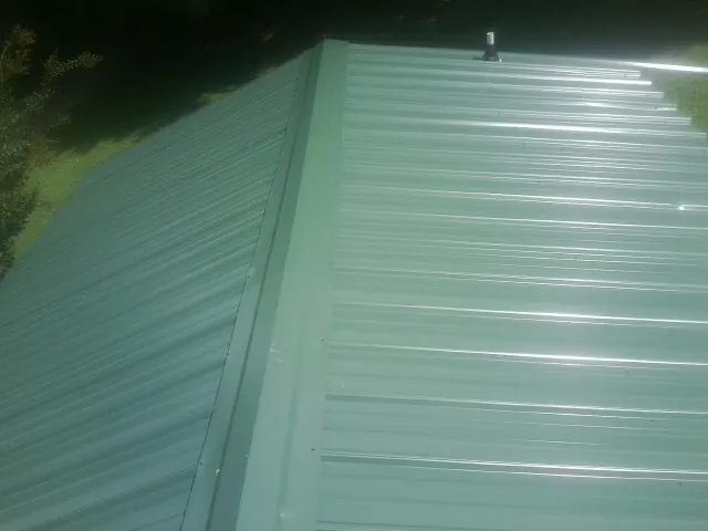 New green metal panels meeting at the ridge of a roof — Flat Roof Repair work by our crew in Barryville