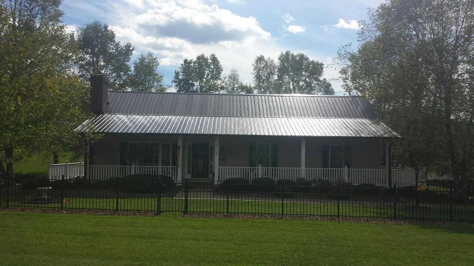 Gray metal roof on a brick ranch with a full width front porch — Gutter Guard Installation work by our crew in Barryville