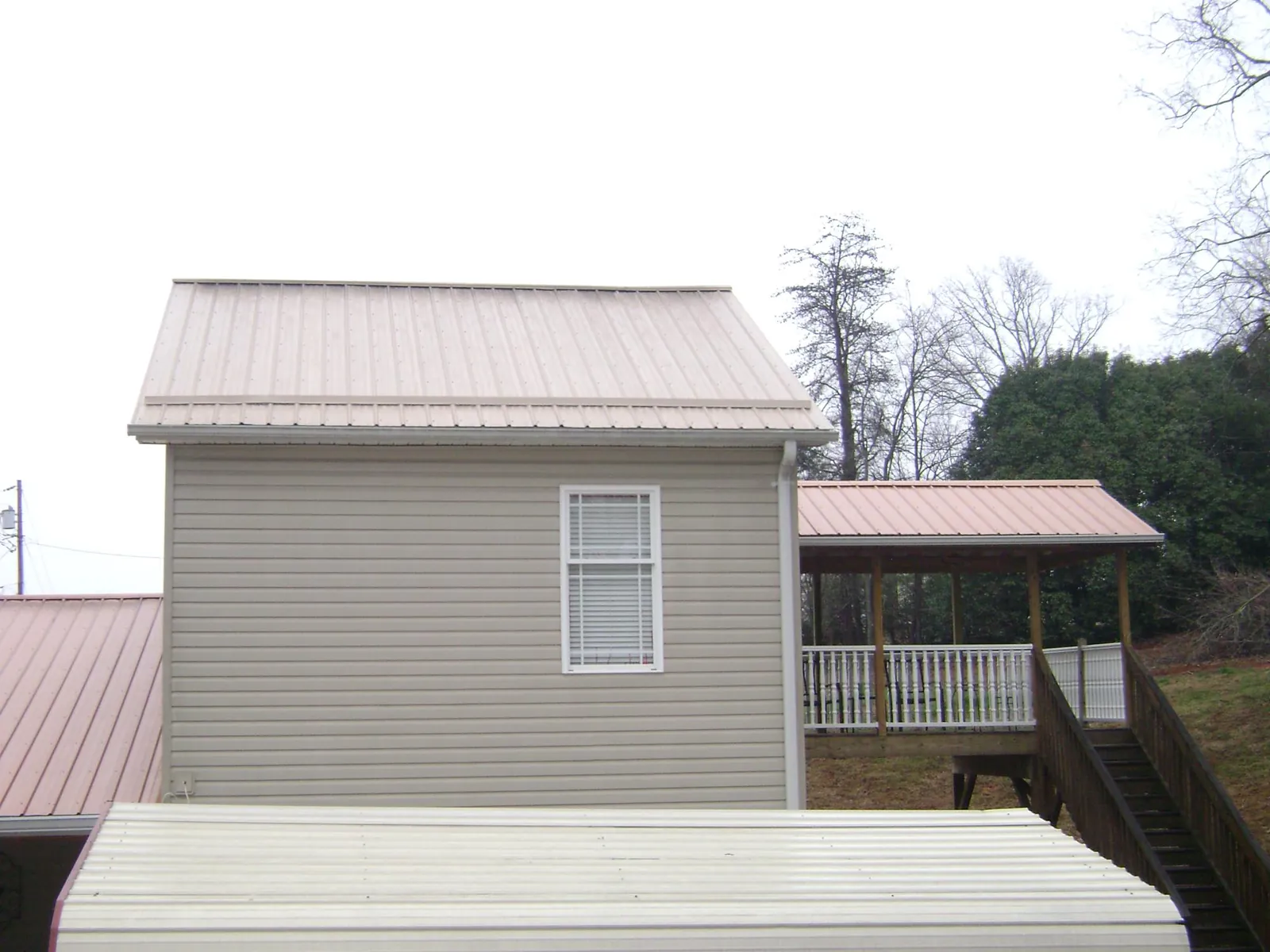 Tan metal roofs on a two story addition and attached porch, from a Roof Replacement job in Barryville