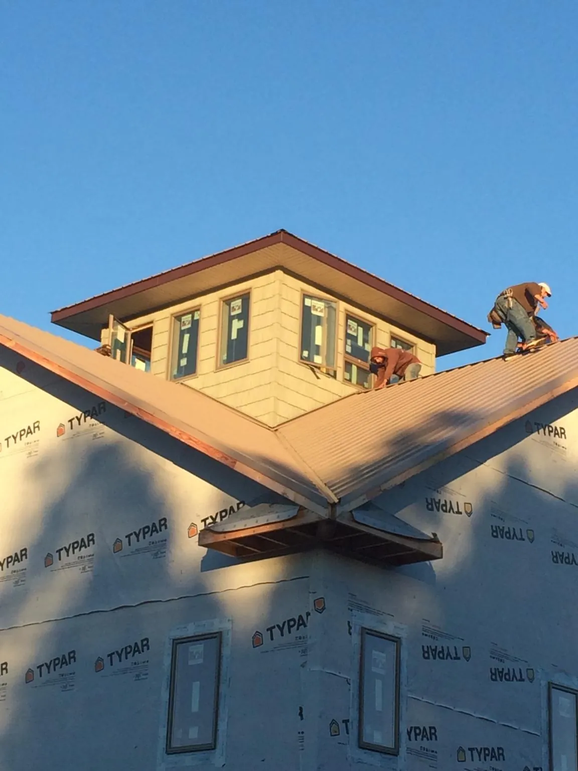 Roofers working around a rooftop cupola on a new metal roof at sunset — Roof Waterproofing in Barryville by Roofing Brothers